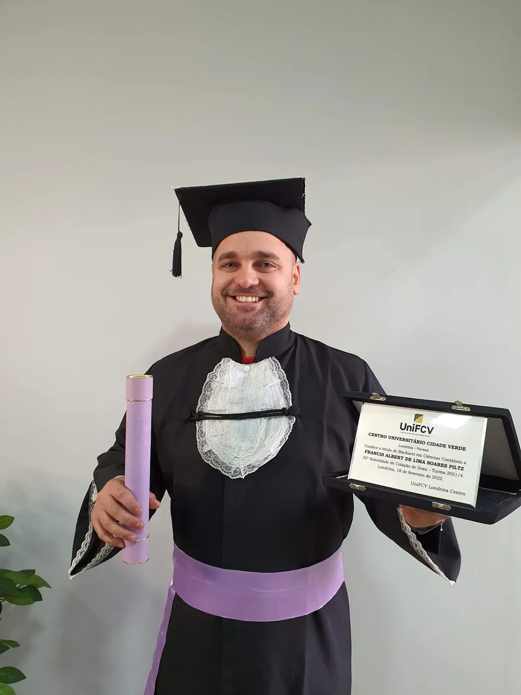 Formando segurando a placa comemorativa e o canudo da colação